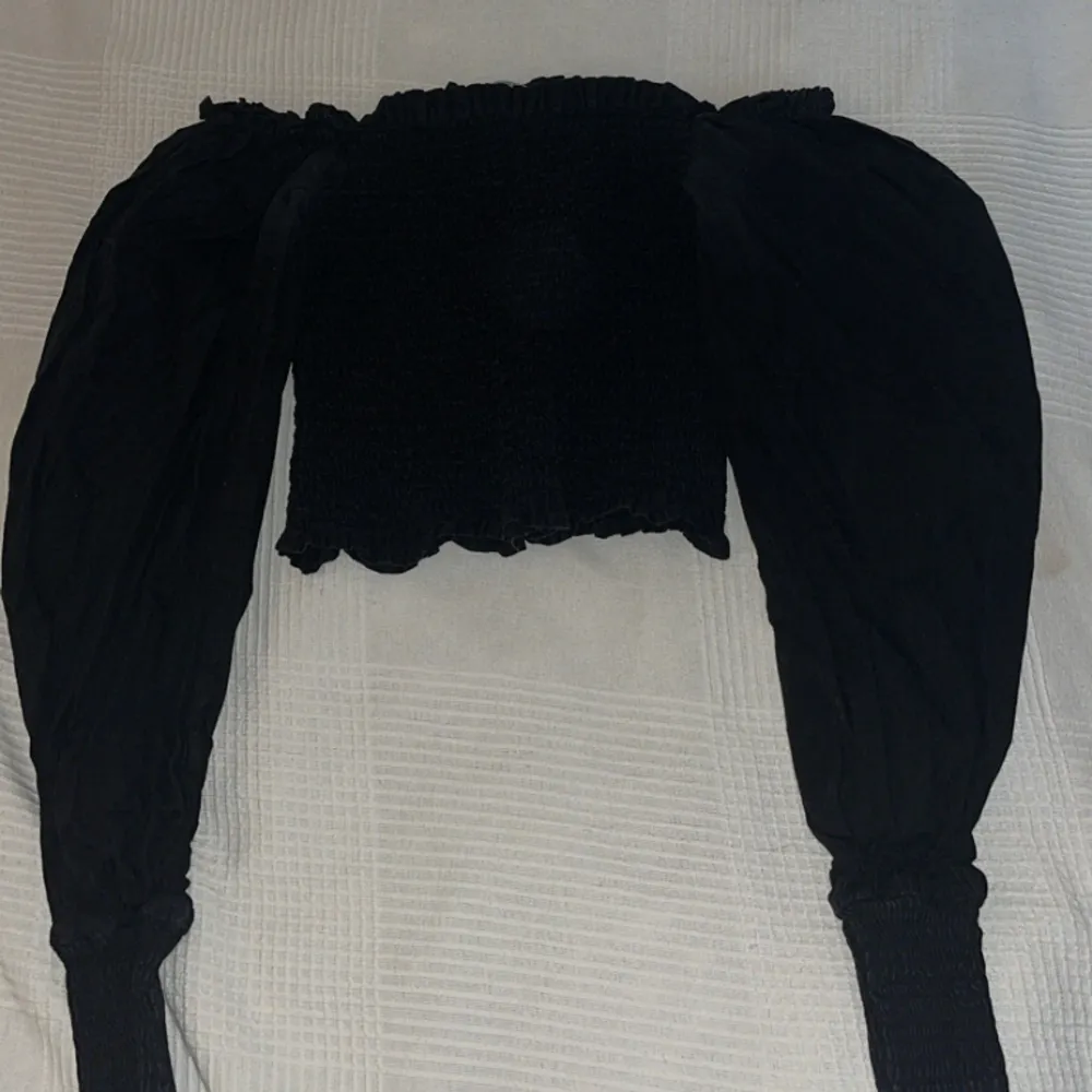 Säljer en svart långärmad blus  med puffärmar från ginatricot i storlek S. Blusen har rynkningar fram och bak och i blusen och där nere vid armarna. Blusen är perfekt för att skapa festliga outfits och har en klassisk svart färg. . Blusar.