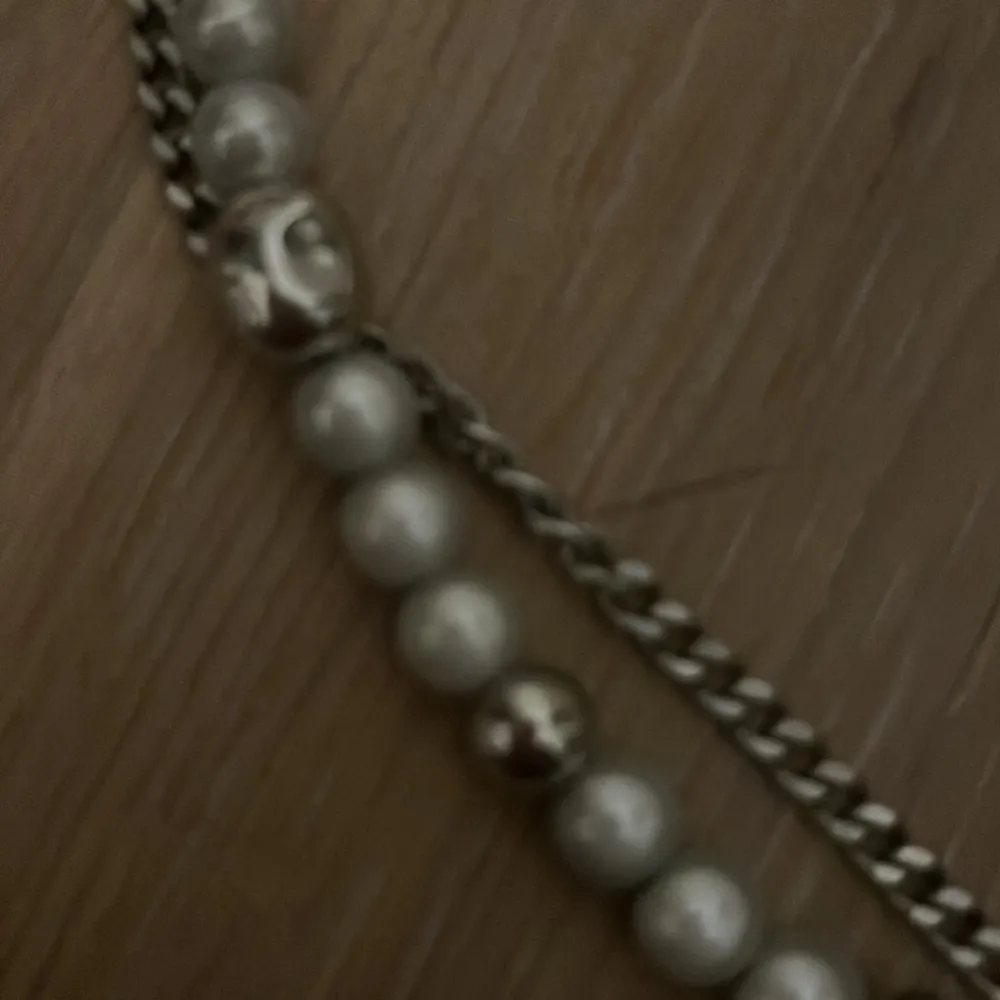 Ett helt oanvänt korshalsband med silvriga pärlor med en kedja runt. Väldigt litet och kan användas som en chocker om man vill. . Övrigt.