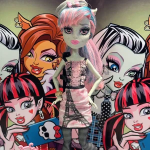 Rochelle Goyle Monster High -12 - Snygga Rochelle Goyle Scaris City Of Freights G1 -12 Hon är klädd i sin snygga orginalklänning, svarta strumpbyxor, dom rosa läckra skorna & den grå baskern med rosa rosett Rochelle har oxå ett strassarmband & sin grå resväska. Det ingår en ställning