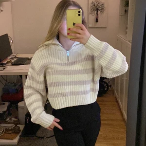 Stickad zip - En lila randig stickad tröja med half zip. Lite kortare i modellen, från Gina tricot. Köparen står för frakten.