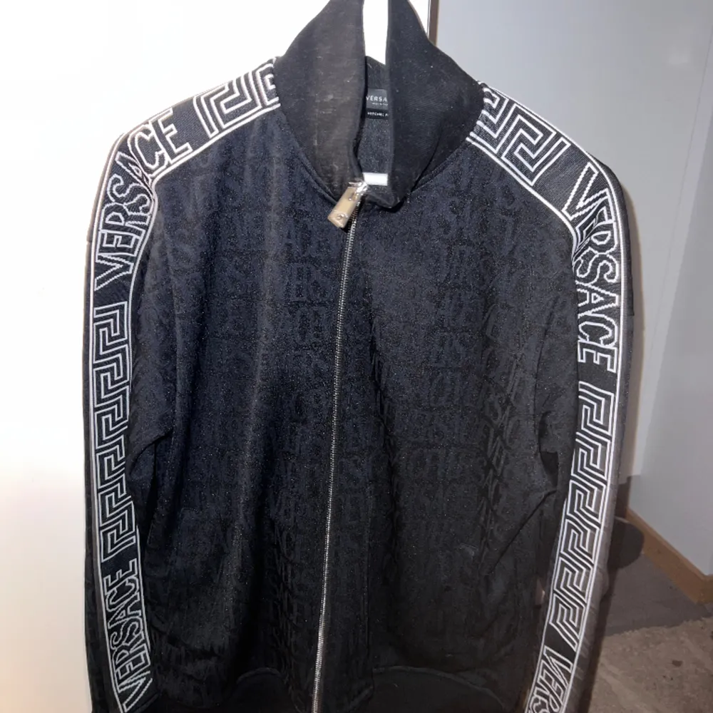 Versace tröja utan luva, använd fåtal gånger. Inköpt från NK för 15.000 kr. Storlek M men passar även L. Tillverkad av svart bomull, har den signatur Greca-detaljering och ett iögonfallande Versace Allover-mönster. . Hoodies.