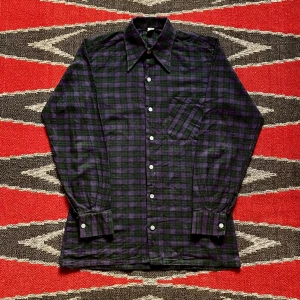 70-tal, Flanellskjorta  - Urtjusig rutig skjorta med dolk-krage från 70-talet. I superfin rejäl bomullsflanell i lila och grönt och med schyssta pärlemorknappar! Längd-70cm Axlar-38cm Bröst-43cm Midja-43cm Ärm-54cm. Priset är förhandlingsbart! ⭐️