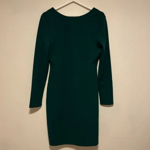 Mörk grön klänning med öppen rygg - Bra skick, oskadad, jätte fint material, man kan ha på klänning på båda håll alltså ena med öppen rygg och andra med öppet fram