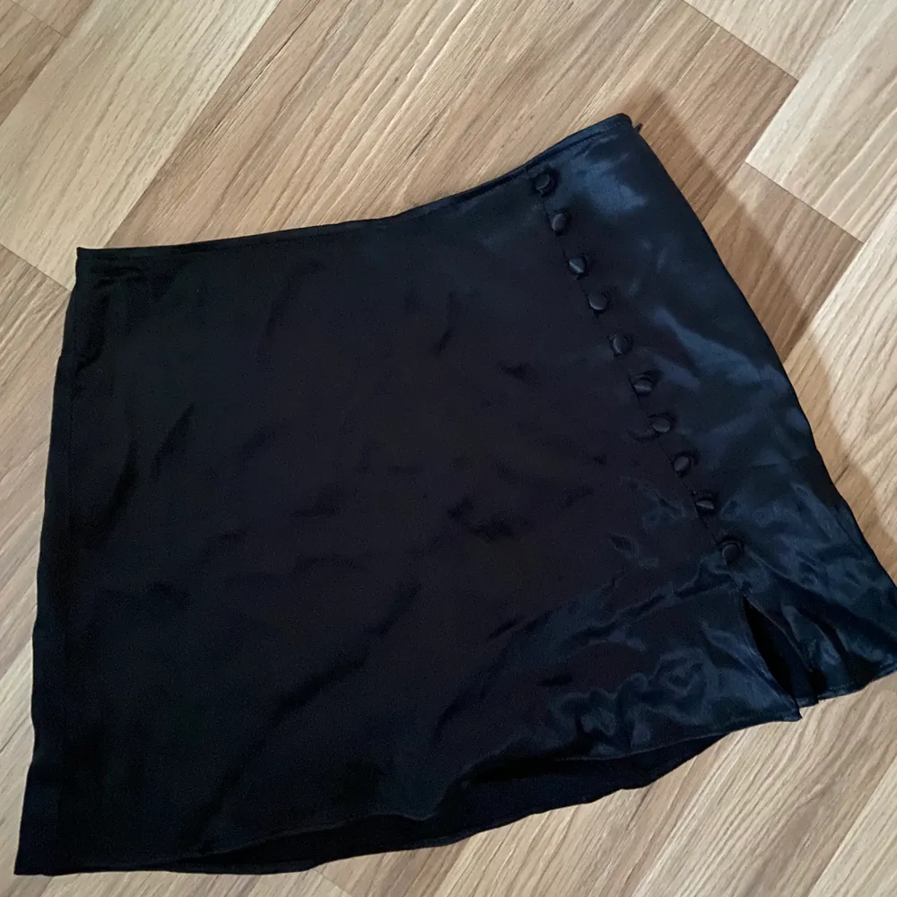 En svart satin/siden kjol med knappar från Zara💫 Kjolen har shorts under vilket är väldigt praktiskt och bra. Den är i storlek S men skulle även passa en XS eller M🥰 Bara använd 1 gång och köptes för 299kr, säljer nu för 200kr! . Kjolar.