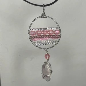 Handgjort kristall halsband  - Egengjort silver och rostfrittstål hänge med en rosenkvarts kristall och äkta läderkedja.   Rosenkvarts är en kristall för kärleken till oss själva. Den lugnar oss och ger oss tröst. Den stödjer oskuldsfullhet, sårbarhet och tillit. Den ger oss kärlek utan villkor och krav.  Stjärntecken: skorpionen Månadsten: oktober Chakra: hjärta, navel och bas 