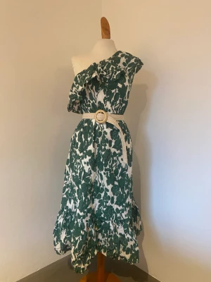 Klänning - Grön mönstrad klänning med sidovolang och skärp o midjan. Midi/ maxi. Strl M från Mango. Ny med taggar.