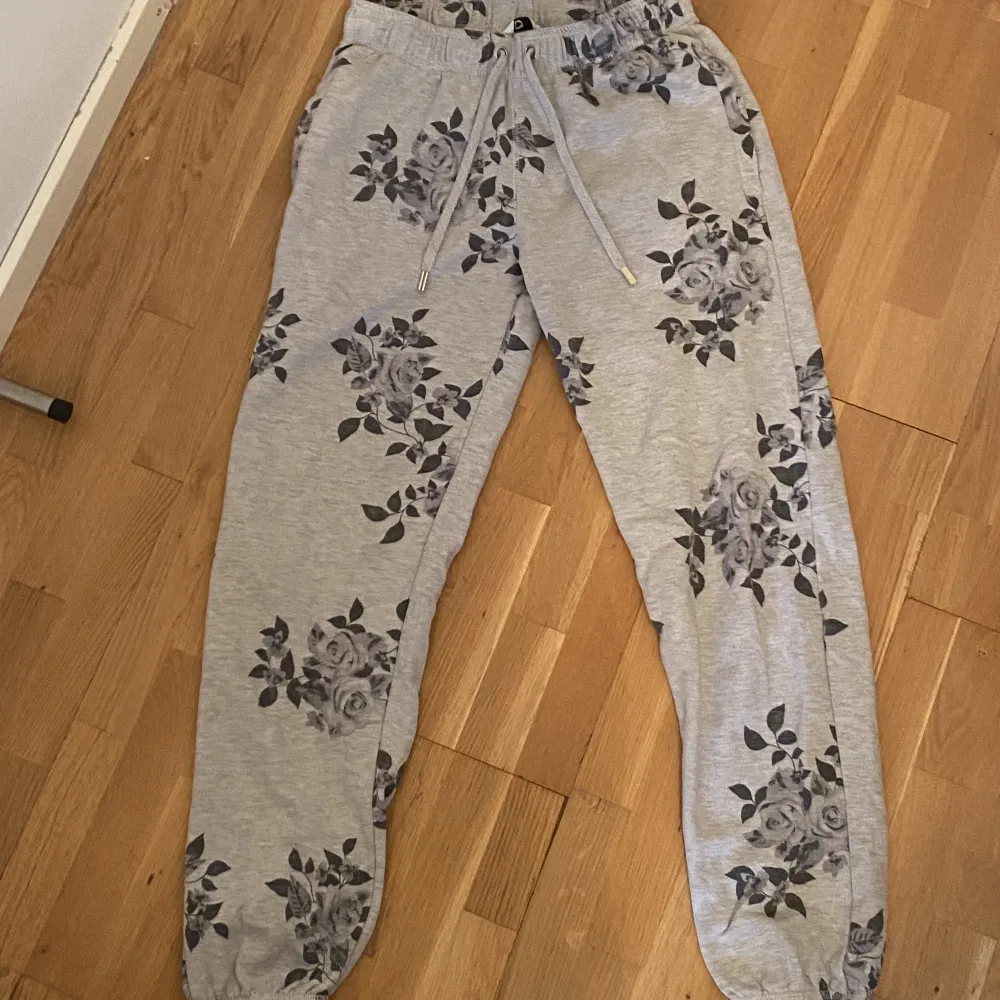 Gråa mjukisbyxor med blommor, inga tecken på användning. Jeans & Byxor.