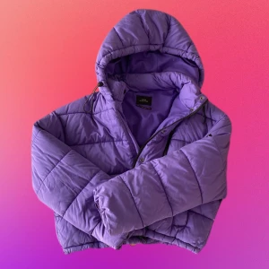 Lila puffjacka  - Superfin och mysig vinterjacka. Croppad i längden och har både dragkedja och knappar. OBS jackan har ett håll vid knappen vid kragen, syns ikke när man stänger jackan men det är bra att veta om.