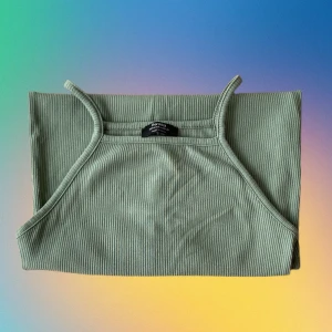 Grön mini klänning  - Somrig grön klänning med ribbat tyg. Klänning är kort och har en halterneck/ fyrkantig överdel. Är i nyskick.