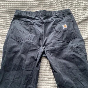 Svarta single knee Carhartt jeans - Snygga svarta baggy Carhartt jeans som knappt är använda. De är lite stora vid midjan så bälte behövs ksk men annars är de översnygga och sköna baggy jeans.