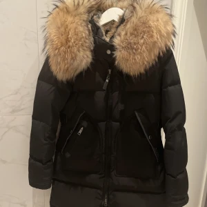 Cedrico Monet XXS svart - Svart dunjacka från Cedrico i modellen Monet. Storlek XXS. Sparsamt använd under två säsonger då jag har andra jackor att växla med. Fantastiskt stor och fluffig päls, pälsfodrad luva.