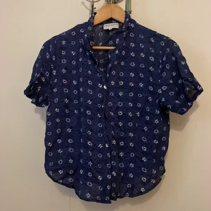 Skjorta  - Blå kortärmad skjorta med små vita blommor på. Frakt tillkommer 