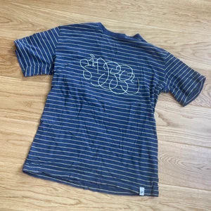 Stussy TSHIRT  - Blå gul randig stussy tshirt med ett sjukt fett ”stussy” tryck. Köptes för 2 år sedan men kmr aldrig till användning längre. Sparsamt använd.  Size L men passar M också.  Säljes för 170kr men priset är diskuterbart. 