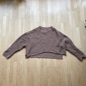 Brun stickad tröja ifrån Urban Classics  - En brun stickad tröja i storlek s ifrån Urban Classics. Längden på tröjan är 50 cm och därav lite kortare än en vanlig stickad tröja. Den är ändå oversized och har en slits på vardera sida. Fler bilder kan fås! Kan skickas