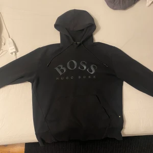 Hugo Boss Hoddie - En svart hugo boss hoddie som är använd men i gott skick inga defekter väldigt skön, storlek L men passar även mig som har medium