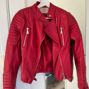 Skinnjacka  - Säljer den röda skinnjacka från chiquelle. Den är använd men det finns inga spår av några hål eller fläckar. Jackan har snygga silver detaljer både fram och på sidorna. 