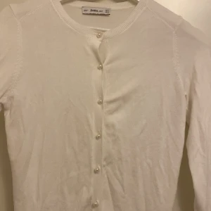 Zara kofta Vit - Säljer denna vita kofta från Zara, då den inte kommer till användning. Superfina knappar och funkar perfekt till hösten. Säljes för 100 kr. 