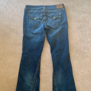 True religion lågmidjade bootcut jeans - True religion jeans som e lite bootcut med sjuk stitching använda kanske 4 gånger. Modell Joey Big T storlek 32 sitter perfekt på mig som är 180 men skulle säga att de passar 170-185