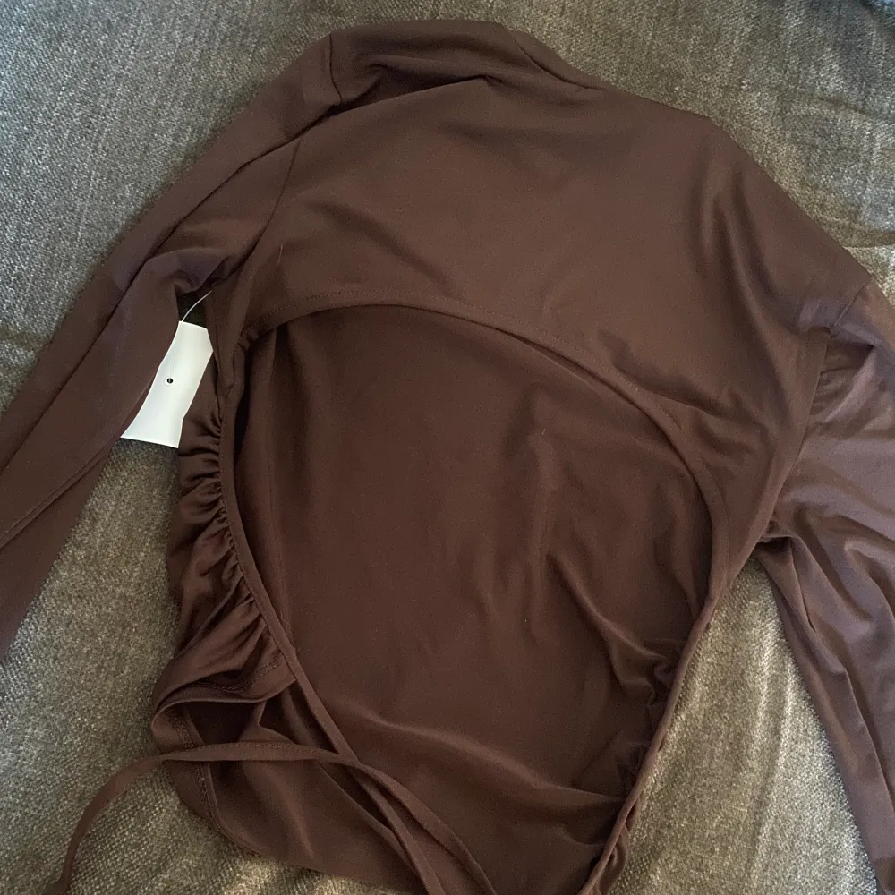 Helt ny oanvänd tröja som knyts i ryggen 😍 med alla lappar kvar!!. Köpte för ungefär 250kr.  Den är i en mörkbrun färg (mörkare i verkligheten än på bild)  och i så himla skönt material.. Toppar.
