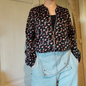 Tunn jacka - En blommig jacka som funkar bra som accessoar till en outfit. Den är ganska tunn så den hade inte funkat som en funktionell jacka för att hålla värme. Den är i barnstorlek men passar mig som brukar vara en str S. Frakten ingår inte i priset