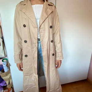 snygg Trenchcoat  - En beige trenchcoat från Vero Moda, perfekt nu till hösten! Passar både som öppen och knäppt med antingen knapparna eller knytning