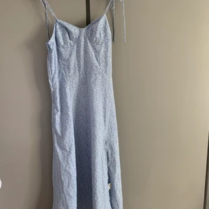 Blå klänning med vita blommor  - Storlek 36