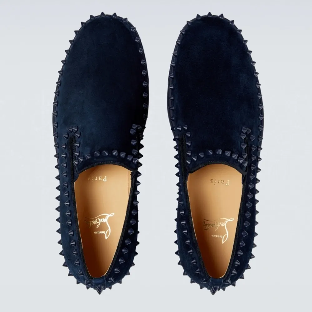 Low-top suede slip-on sneakers in navy. Signature stud detailing throughout.  · Elasticized gussets at vamp · Buffed leather lining · Signature red rubber sole  Supplier color: Marine/Marine mat Upper: leather. Sole: rubber.  Made in Italy.     . Skor.