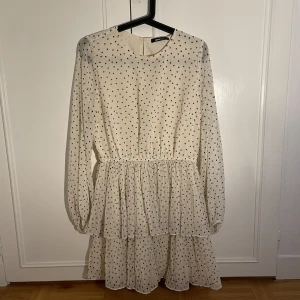 Prickig klänning - En vit prickig klänning från Gina Tricot. Knapp i nacken och resår i midjan. Aldrig använd. Storlek 38. 