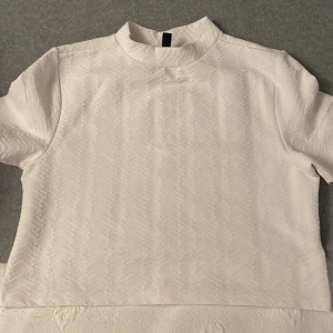 Topp H&M divided  - Kortärmad topp, rak passform, rund halsringning. Gjorda i 96% polyester, 4% elastan. Secondhand använd fåtal ggr i finskick. Längd 41 cm i stl EU small.