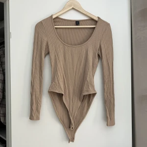 Body långärmad - Brunbeige långärmad body från Shein strl. S. Oanvänd. 70 kr Samfraktar gärna! Kolla in mina andra annonser om det finns något av intresse!