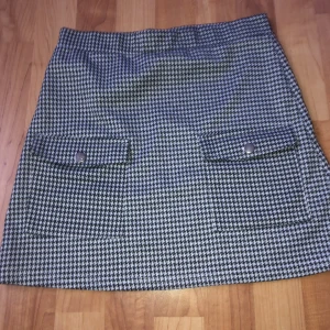 Kjol - En svart vit kjol med fickor i fram som kan öppnas  .