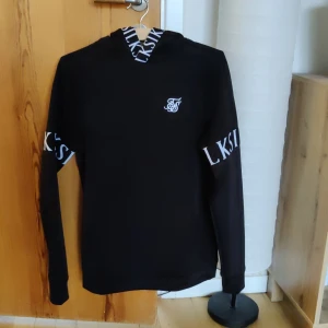 Siksilk hoodie svart - Köptes för ett par dagar sedan. För liten i storlek (S) och kan ej returneras. Därav säljs den här.   Mer info:  https://www.zalando.se/siksilk-dynamic-overhead-hoodie-luvtroeja-black-sif22s0jb-q11.html