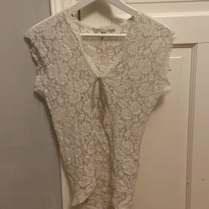 Vit topp med en knytning  - Storlek S har modellen (jag). Rosmönster, använder både till fest och andra tillfällen. 
