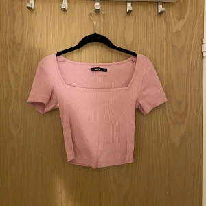Rosa topp - Rosa topp ifrån BikBok med regtangulär halsringning. Ganska kort. 