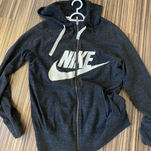 Huvtröja med dragkjedja - Tunn hoodtröja med dragkjedja i fint skick från Nike, perfekt träningströja. Den har även luva, färgen är lite gråmelerad