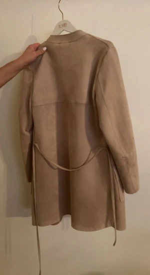 Mockakappa - Säljer en beige mockakappa i storlek 34. Köpte för 600 och säljer den för 250+frakt. Oanvänd kappa i bra kvalite säljs för att den är för liten.