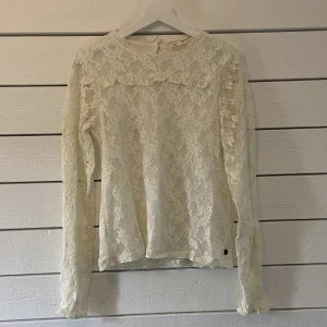 Vit blus i spets  - Vit blus i spets med ett fint blommigt mönster från Kappahl. Använd vid 2 tillfällen. Den är köpt från barnavdelningen och har storleken 170. Jag motsvarar S/M och kan bära den utan problem! Tillkommer frakt!🤍