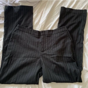 Lågmidjade kostymbyxor  - Lågmidjade kostymbyxor med vita ränder. Har ett hål som jag har sytt igen (syns på bild 2) men annars inga defekter. Passar S-M. 