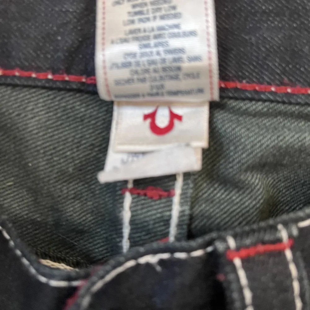 Nästan helt nya true religion jeans cond 9,5 Storlek 30  byxorna är straight fit och har fet röd vit stich över hela byxan. Jeans & Byxor.