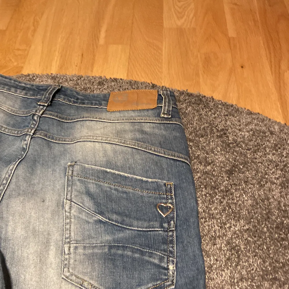 Detta är ett par blåa jeans i storlek medium.Det finns ett hjärta i silver på baksidan på höger ficka.Hålen är menade/det ska vara så. Byxorna är i  fint skick. . Jeans & Byxor.