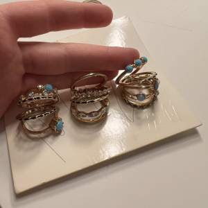 Guldringar från HM. Säljer då de är för stora för mig. Ringarna är aldrig använda. De mindre ringarna är till för att ha på övre del av fingrarna och de är endast provade och inte användna. Ingen av ringarna har tappat färg. Vissa har blå ”sten” detaljer 