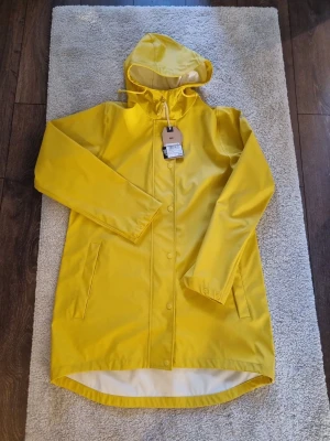 Regnjacka Petra strl 44 - Regnjacka från Weather report. Petra W Rain jacket.  - Normal passform - Dold dragkedja - Luva med dragsko - Öppna sidofickor - Vind och vattentät - Tryckknappar i ärmslut - Ofodrad