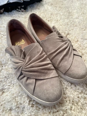 Dasia skor - storlek 38 - Gråa Dasia skor o storlek 38. Köptes för ca 700kr. Använda ett fåtal gånger. Det syns att skorna är använda pga fläckar/märken. I övrigt är de i bra skick.  Jag kan frakt, köparen står isåfall för fraktkostnad. 