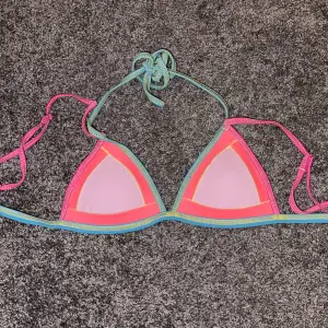 Neon färgad bikini topp med sömmar. Väldigt fin och framhäver huden framförallt om man är lite solkysst. Använd endast en gång. Har knytband runt nacken och ryggen plus axelband. 💘🌈