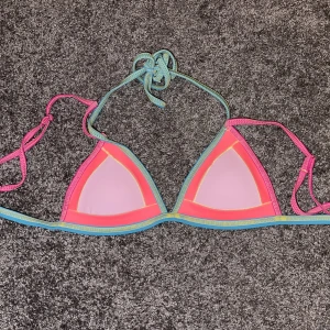 Bikini top - Neon färgad bikini topp med sömmar. Väldigt fin och framhäver huden framförallt om man är lite solkysst. Använd endast en gång. Har knytband runt nacken och ryggen plus axelband. 💘🌈