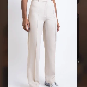Högmidjade Kostymbyxor Utan Fickor - Hazel Off White - Helt nya kostymbyxor från madlady, prislappen sitter kvar och dem är endast testade. Säljer då dem är för stora för mig och kommer inte till användning. Nypris 599 kr på deras hemsida💞