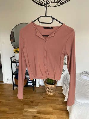 Långärmad med knappar - Supersöt tröja som aldrig är använd. Småribbad. Tack vare knapparna funkar den även utmärkt som en kofta.