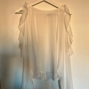 vit blus - vit blus med hål vid armarna. långa armar som sitter åt längst ner. lite genomskinlig 