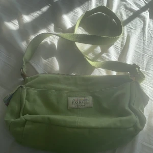 Väska - Jag säljer denna jättegulliga väskan från fossil!💐 den är i bra skick. Bandet går att justera och man får plats med mycket i väskan! Jag säljer pga att den inte är min stil längre men den passar till många stilar!💓