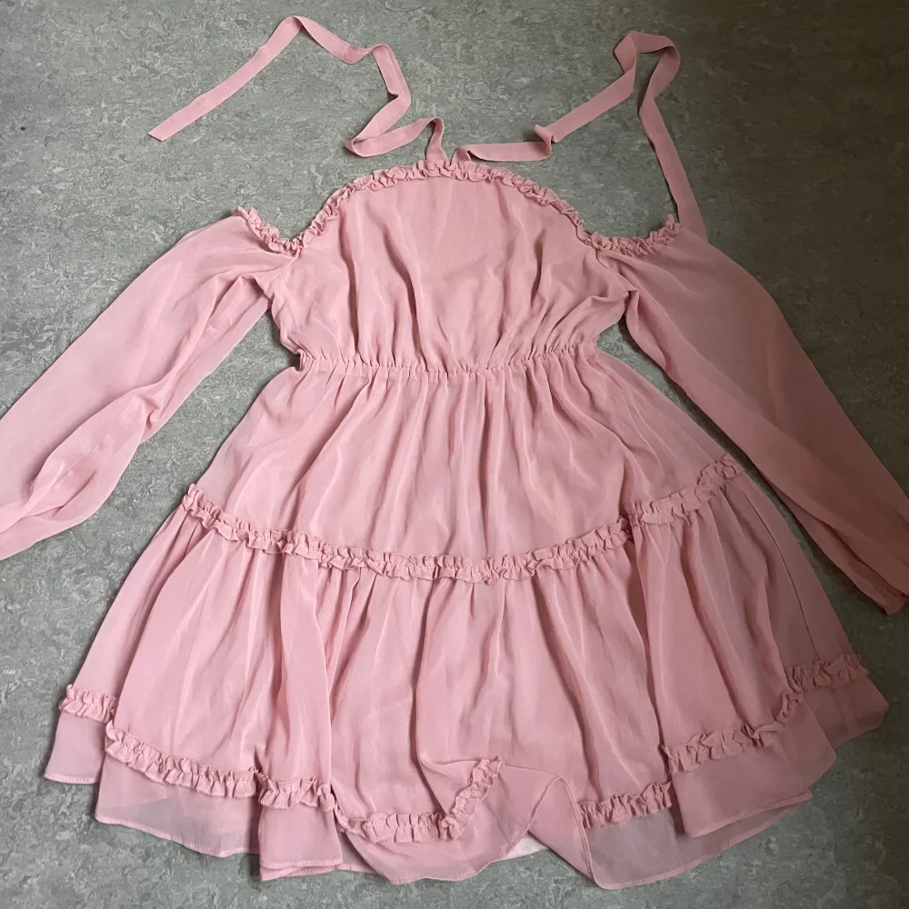 Pink off-shoulder dress with ruffles from nakd, used once. Size 38, fits S and M. The two bands go around the neck. . Klänningar.